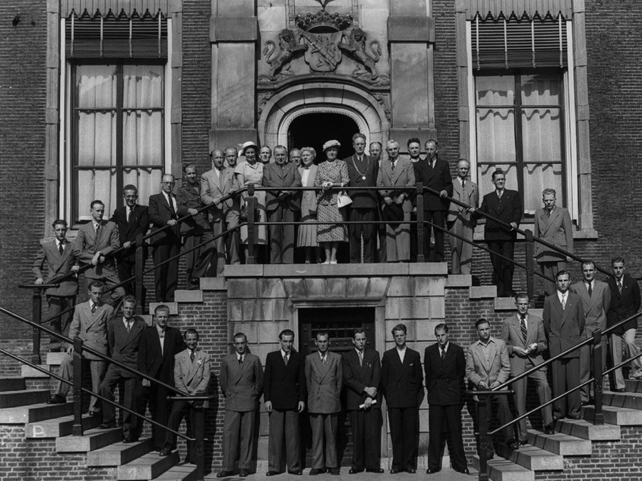 Historische zwart-witfoto van het Stadhuis aan de Grote Markt in Schiedam, met genodigden op de trappen bij de ingang.