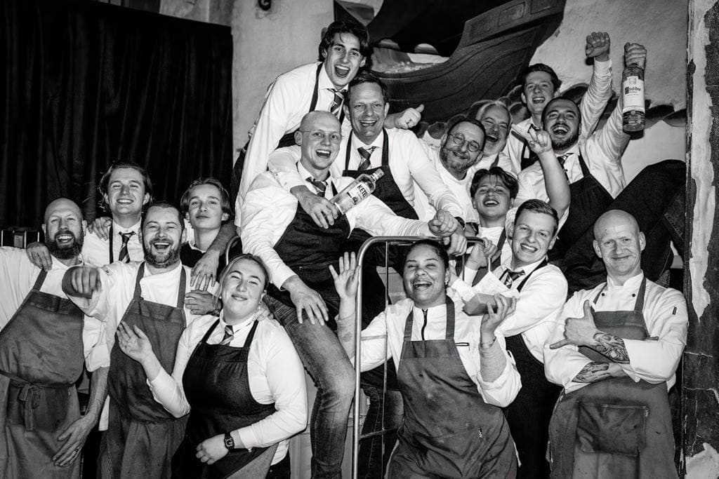 Het voltallige team van Brasserie Stadhuis, uitgelaten verzameld op de trap van de zaak.